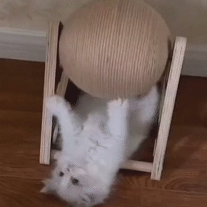 Cat playing with a rotating sisal scratch ball in a wooden frame